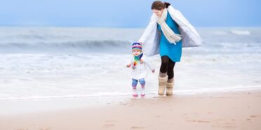 Matka z dzieckiem spacerująca po plaży w zimie