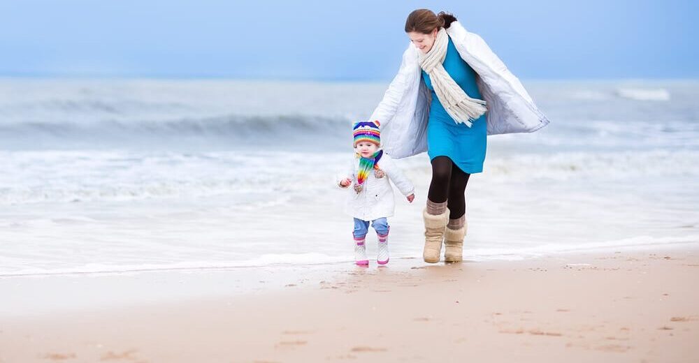 Matka z dzieckiem spacerująca po plaży w zimie