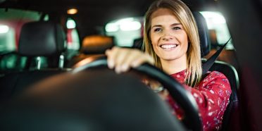 Uśmiechnięta kobieta prowadzi samochód w publicznym garażu